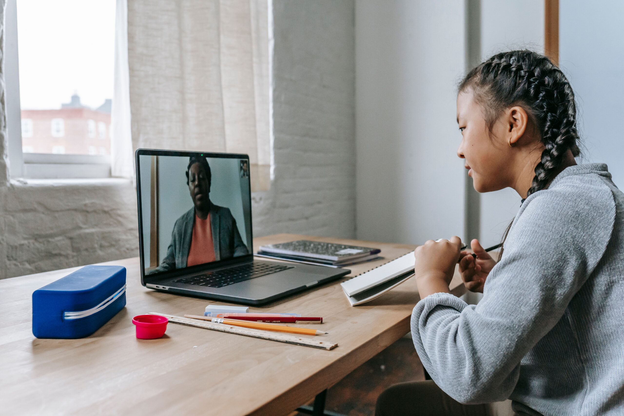 Side view of attentive ethnic girl listening to teacher explaining lesson online on laptop